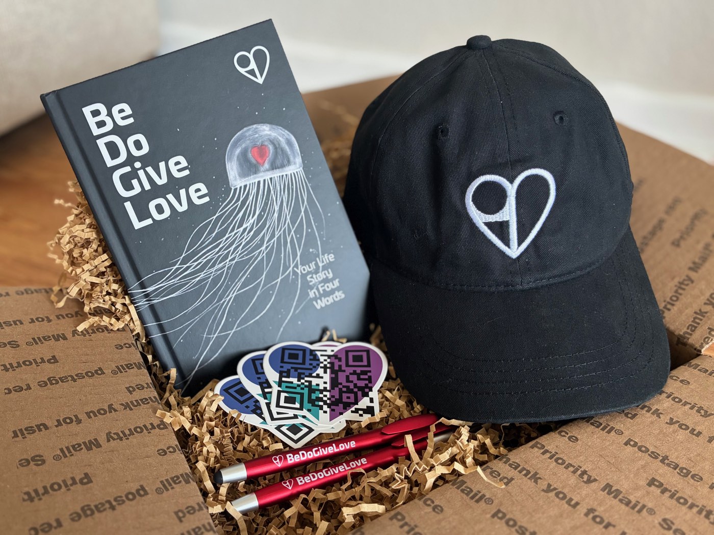 Be Do Give Love hardcover gift box: signed book, embroidered hat, sticker pack, and pens